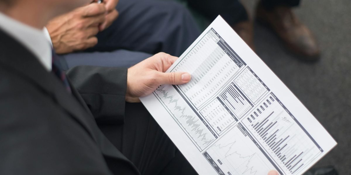A business leader meticulously reviewing a report, symbolizing the importance of measuring the effectiveness of team building investments.