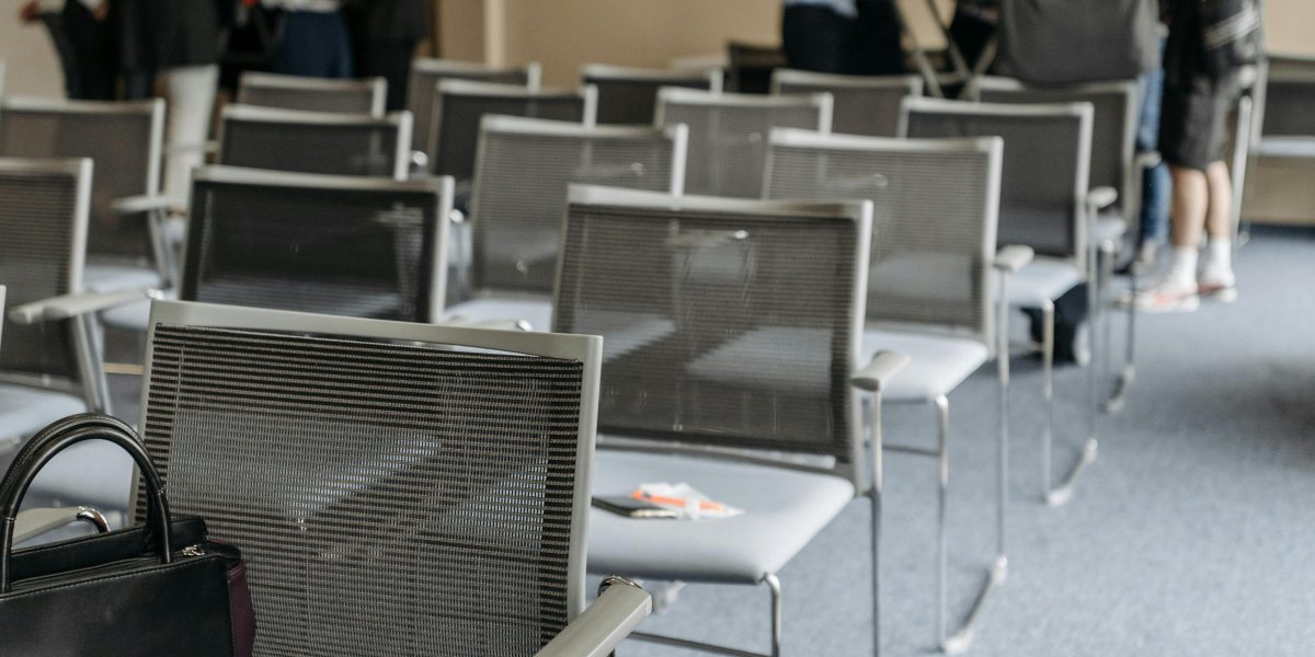 A group of professionals sitting around a table, exhibiting slight nervousness or hesitation before a meeting begins.
