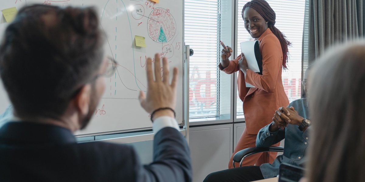 A diverse team actively collaborating and brainstorming ideas on a large whiteboard in a bright, modern setting.