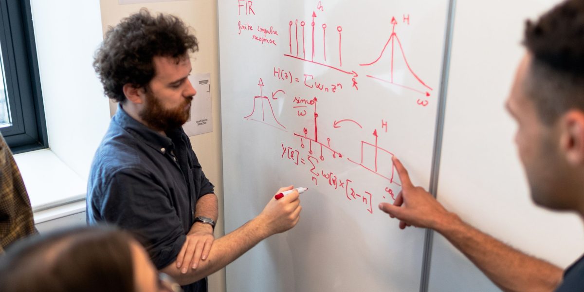A team actively brainstorming and visualizing ideas together on a whiteboard, demonstrating collaborative problem-solving.