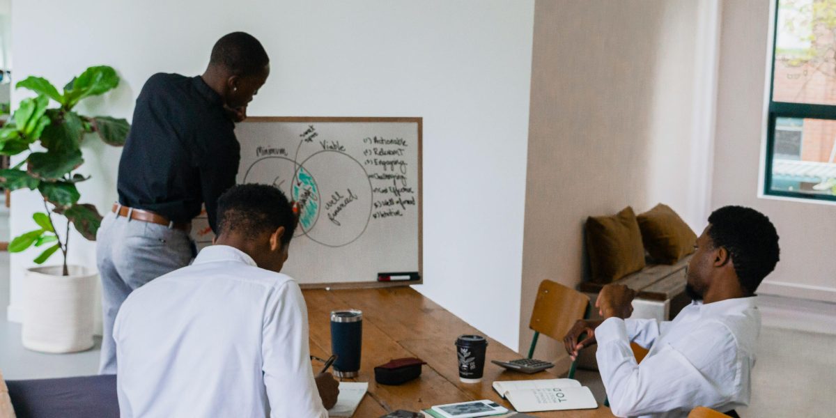 A small team actively brainstorming and solving a problem together using a whiteboard, fostering collaboration.